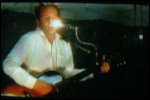 Video still: Martin singing with a light bulb